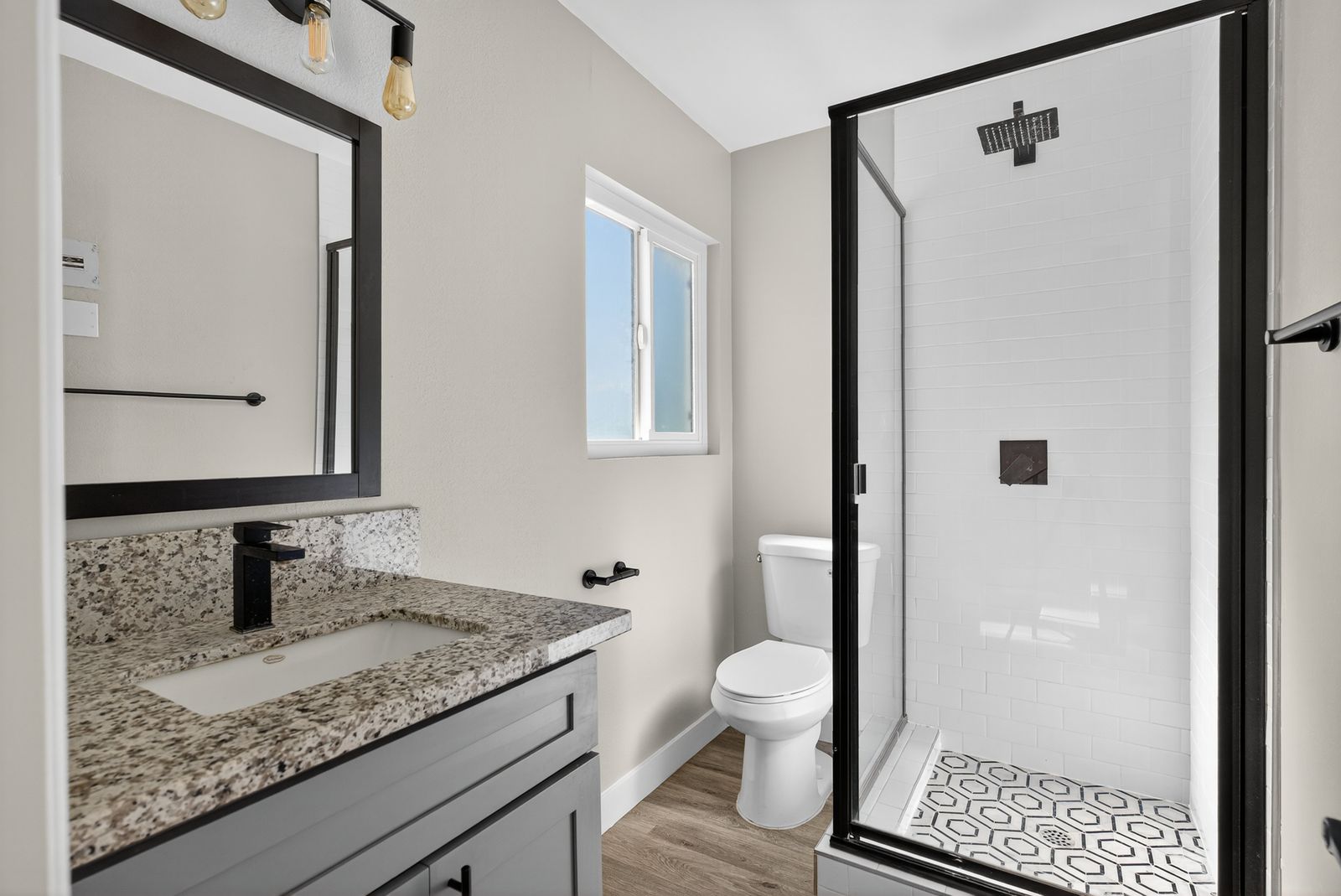 Renovated bathroom with granite vanity and subway-tile shower