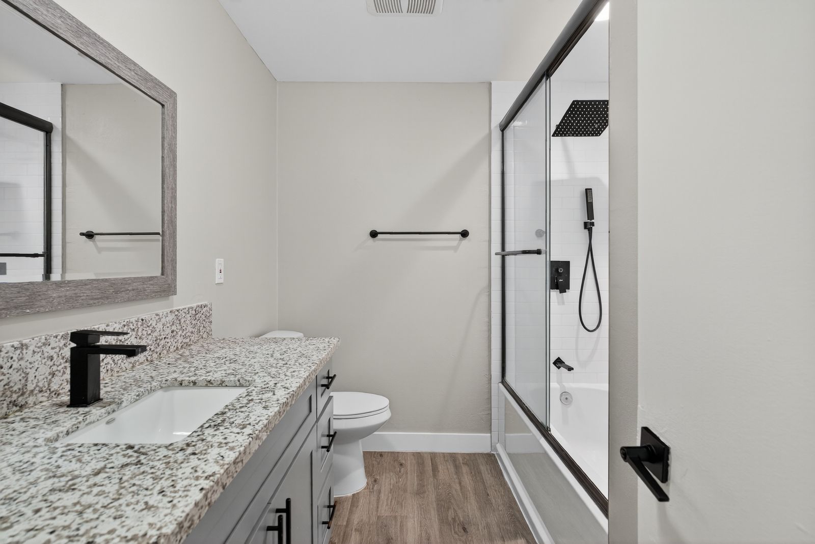 Renovated bathroom with granite vanity and glass tub/shower combo